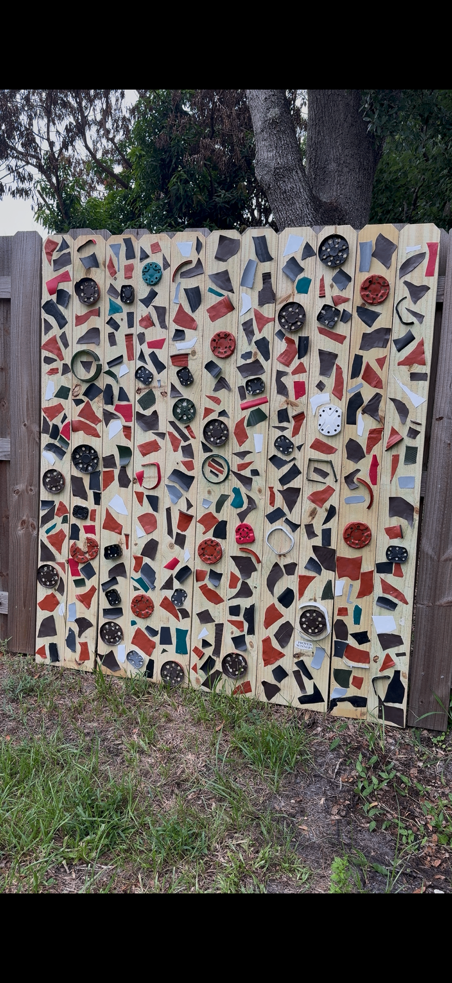Colorful ceramic and tile mosaic on a wooden fence